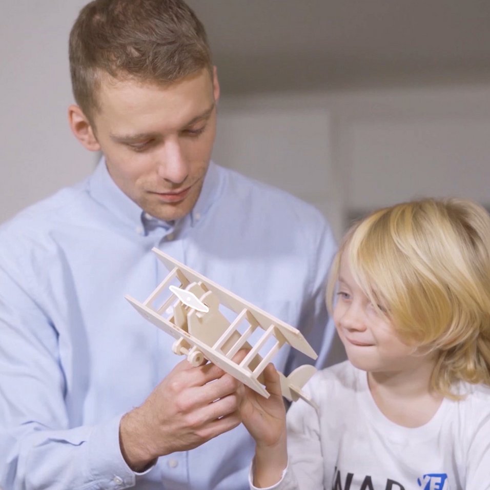 Kind und Vater spielen mit einem selbstgemachten Flugzeug aus Holz