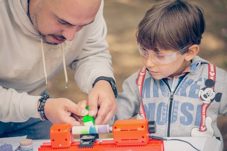 Vater und Sohn arbeiten mit der PLAYmake Drechselbank und bemalen ein Werkstück