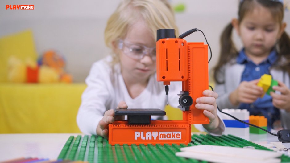 Kind baut die PLAYmake Standbohrmaschine auf einem Tisch zusammen